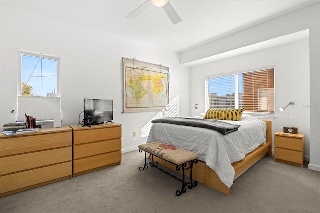 bedroom featuring light carpet, ceiling fan, multiple windows, and baseboards