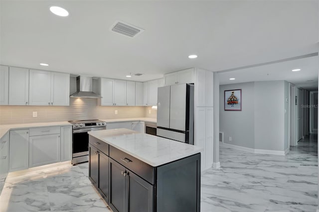 kitchen with wall chimney range hood, electric range, a kitchen island, white fridge, and white cabinetry