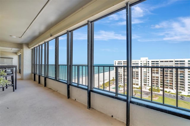 unfurnished sunroom featuring a water view, a beach view, and a wealth of natural light