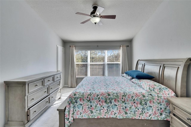 bedroom featuring ceiling fan, light colored carpet, and a textured ceiling