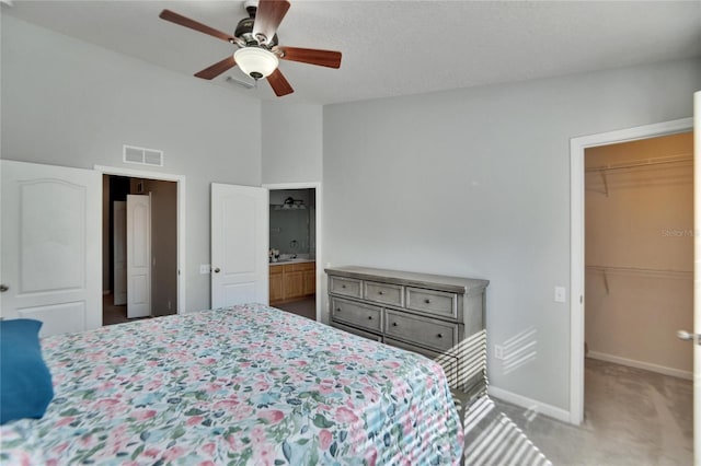 carpeted bedroom with connected bathroom, lofted ceiling, a walk in closet, ceiling fan, and a closet