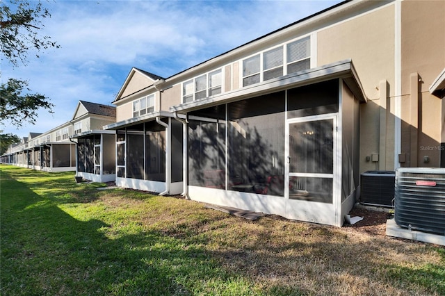 rear view of house featuring a sunroom, a yard, and cooling unit