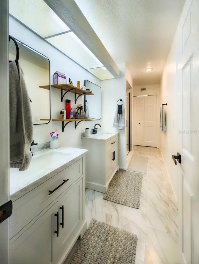 bathroom featuring a stall shower, visible vents, a sink, marble finish floor, and two vanities