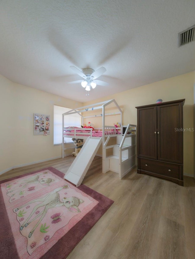 bedroom featuring a textured ceiling, light hardwood / wood-style floors, and ceiling fan