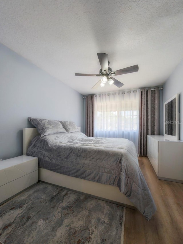 bedroom with hardwood / wood-style floors, a textured ceiling, and ceiling fan