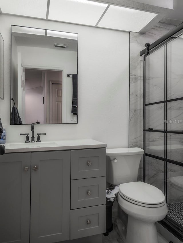 bathroom featuring vanity, toilet, and a shower with shower door