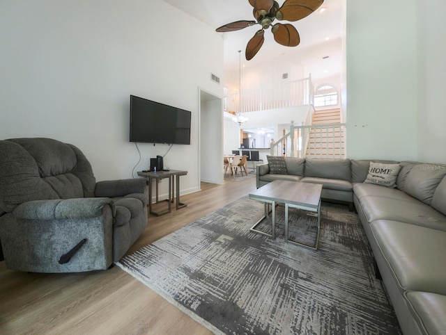 living room with ceiling fan, hardwood / wood-style floors, and a high ceiling