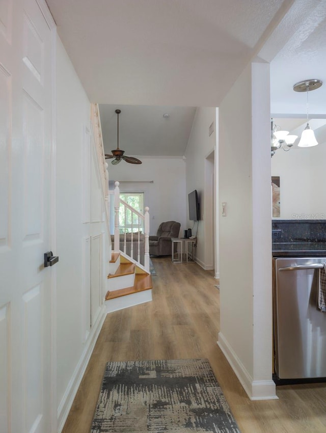 corridor with stairs, baseboards, light wood-style flooring, and a notable chandelier