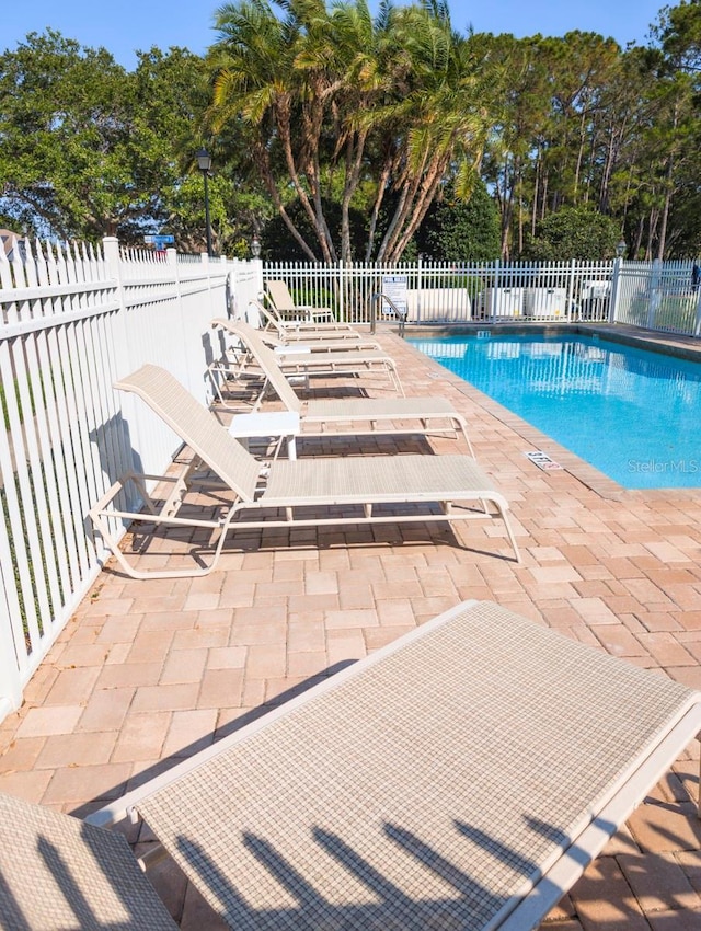 pool with a patio area and fence