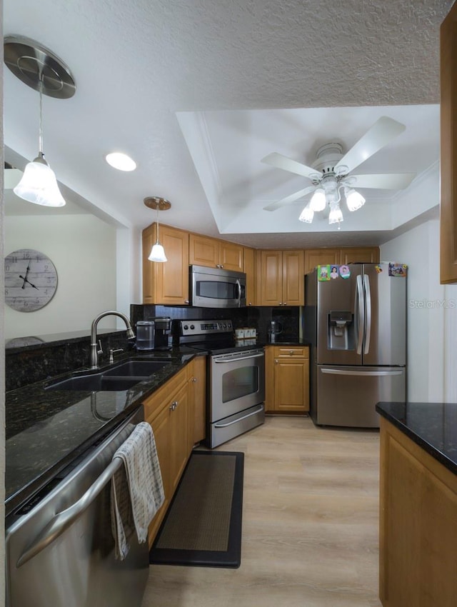 kitchen with appliances with stainless steel finishes, pendant lighting, a sink, and a raised ceiling