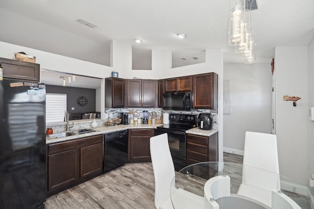 kitchen featuring sink, hanging light fixtures, backsplash, a towering ceiling, and black appliances