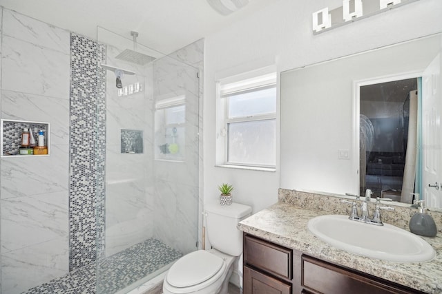 bathroom featuring a tile shower, vanity, and toilet