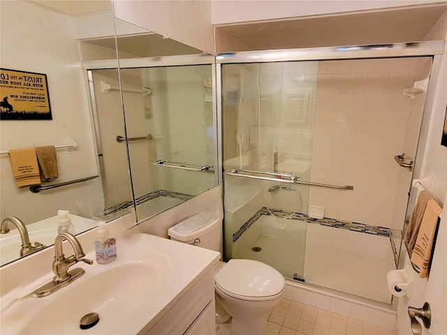 bathroom with tile patterned floors, vanity, toilet, and a shower with door