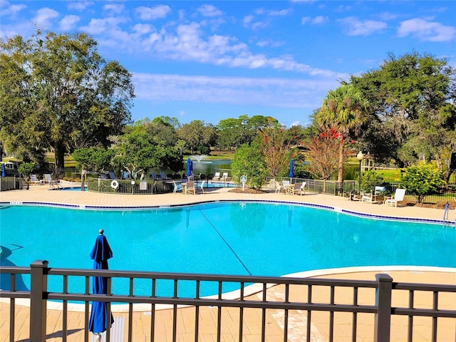 view of pool with a water view and a patio