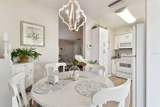 dining space featuring light hardwood / wood-style flooring and an inviting chandelier