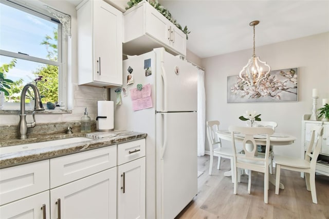 kitchen with white cabinetry, sink, hanging light fixtures, white refrigerator, and decorative backsplash