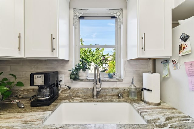 kitchen with tasteful backsplash, white cabinetry, and sink