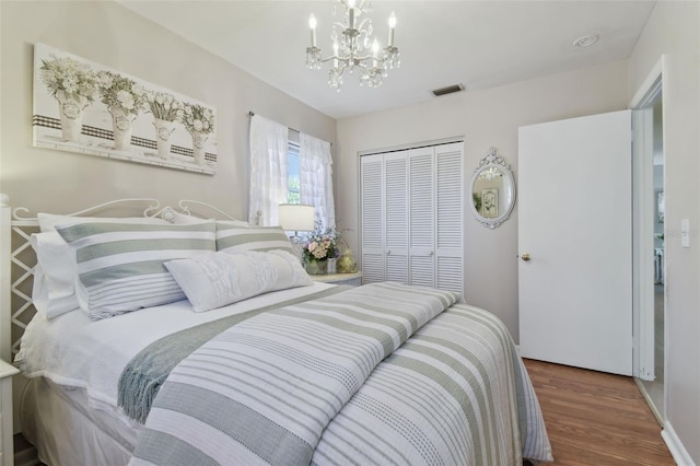 bedroom with a chandelier, dark wood-type flooring, and a closet