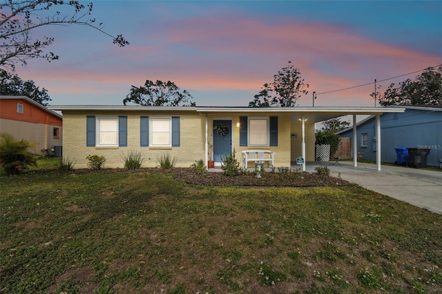 single story home with a lawn, a carport, and central AC