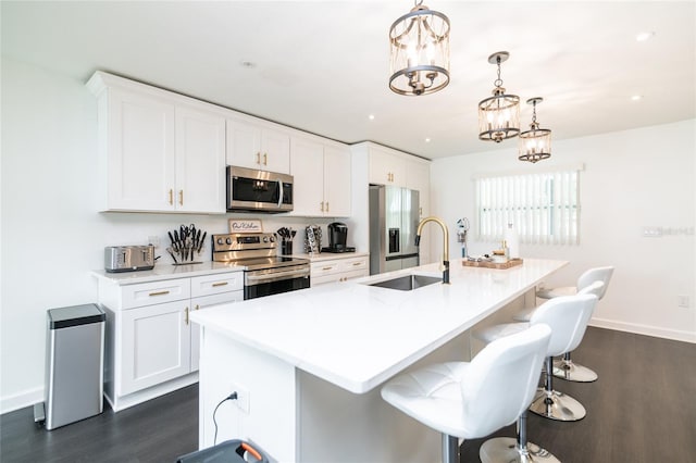 kitchen with sink, a center island with sink, decorative light fixtures, and appliances with stainless steel finishes