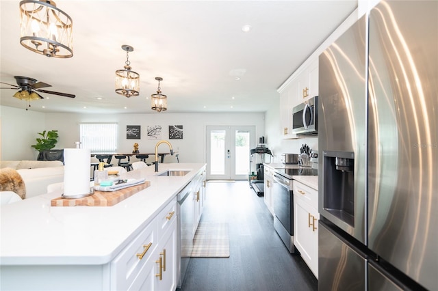 kitchen with white cabinets, hanging light fixtures, sink, an island with sink, and appliances with stainless steel finishes