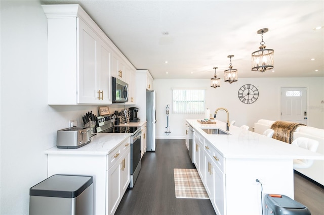 kitchen featuring sink, stainless steel appliances, an inviting chandelier, a kitchen island with sink, and white cabinets