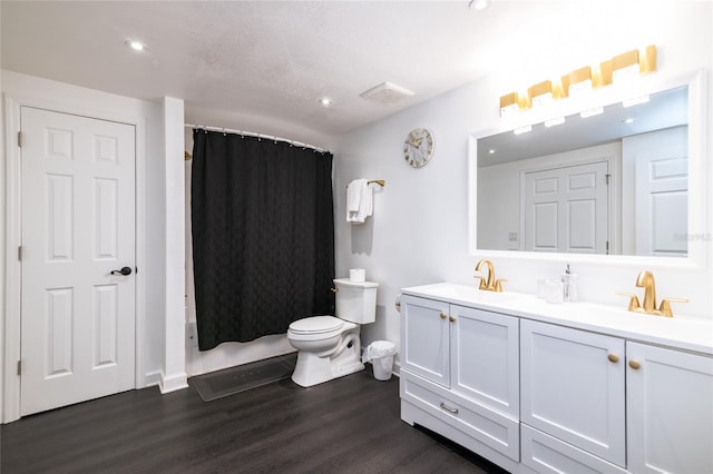 bathroom with walk in shower, vanity, a textured ceiling, wood-type flooring, and toilet