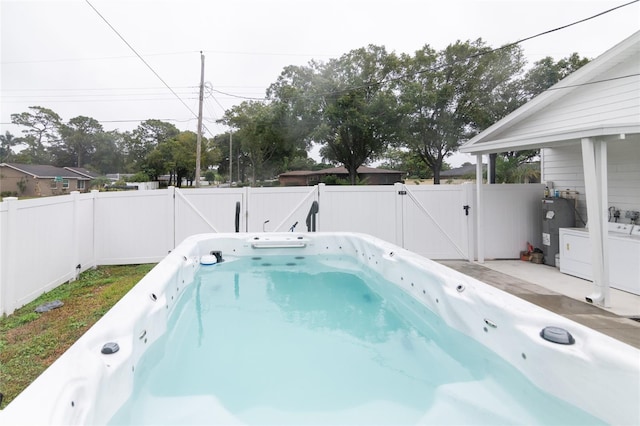 view of pool featuring washer / dryer and electric water heater