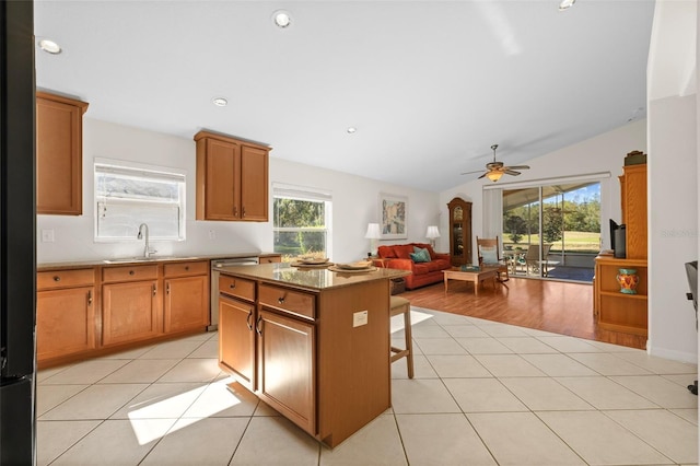 kitchen featuring a kitchen breakfast bar, vaulted ceiling, a center island, light tile patterned floors, and ceiling fan