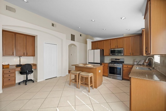 kitchen with light stone counters, a center island, a breakfast bar, appliances with stainless steel finishes, and sink