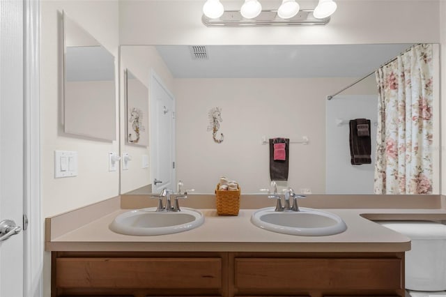 bathroom featuring toilet, vanity, and a shower with curtain