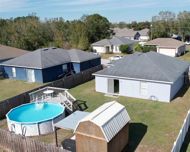 view of pool with a storage shed, a yard, and a deck