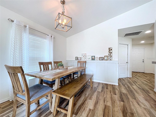 dining room featuring lofted ceiling, hardwood / wood-style flooring, and a notable chandelier