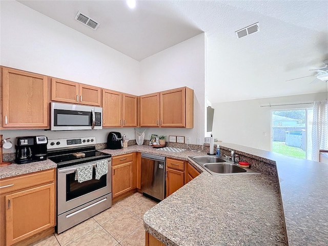 kitchen featuring sink, ceiling fan, light tile patterned floors, kitchen peninsula, and stainless steel appliances