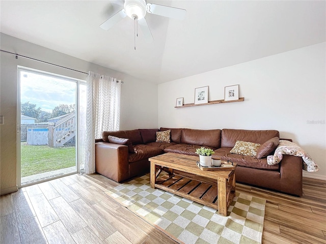 living room with ceiling fan, light hardwood / wood-style floors, and vaulted ceiling