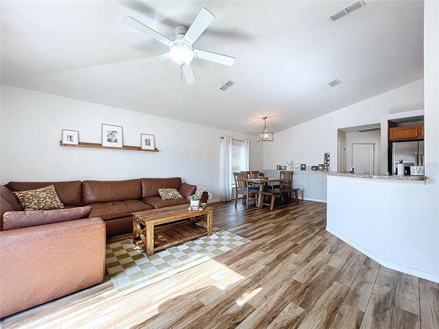 living room with light hardwood / wood-style floors, vaulted ceiling, and ceiling fan