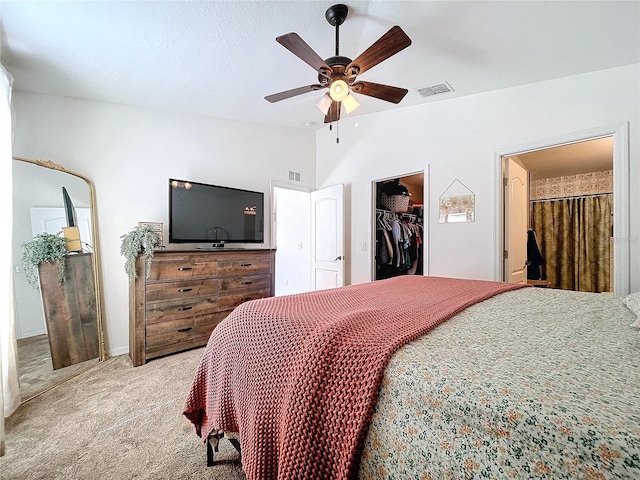 carpeted bedroom featuring lofted ceiling, a walk in closet, ensuite bath, ceiling fan, and a closet