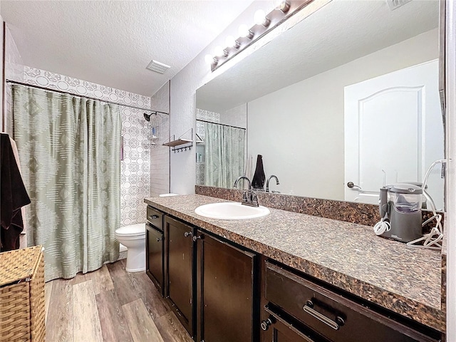 bathroom with curtained shower, hardwood / wood-style floors, a textured ceiling, toilet, and vanity