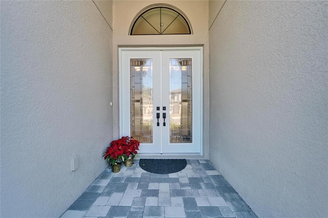 view of exterior entry featuring french doors and stucco siding