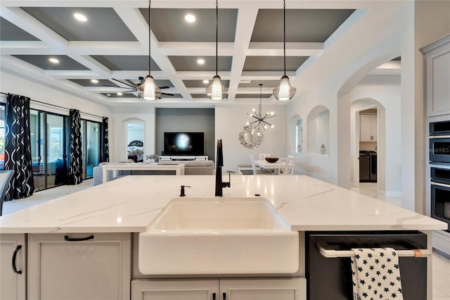 kitchen with pendant lighting, open floor plan, and light stone counters