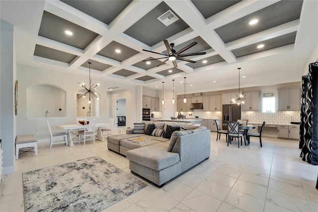 living room featuring coffered ceiling, marble finish floor, visible vents, and ceiling fan with notable chandelier