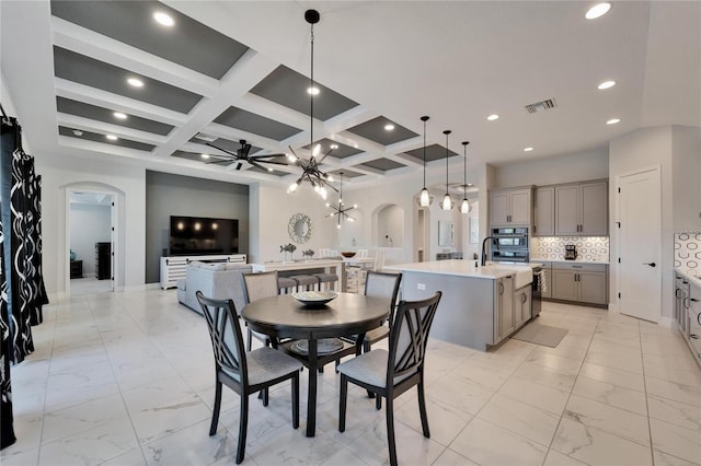 dining space with arched walkways, ceiling fan with notable chandelier, coffered ceiling, visible vents, and marble finish floor