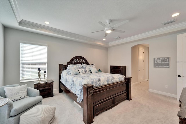 bedroom with arched walkways, light carpet, visible vents, ornamental molding, and a raised ceiling