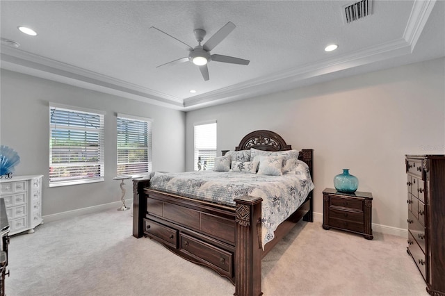 bedroom with light carpet, a tray ceiling, visible vents, and crown molding