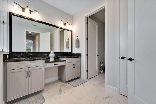 bathroom featuring marble finish floor, a sink, baseboards, and double vanity