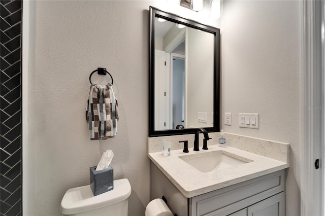 half bathroom with toilet, a textured wall, and vanity