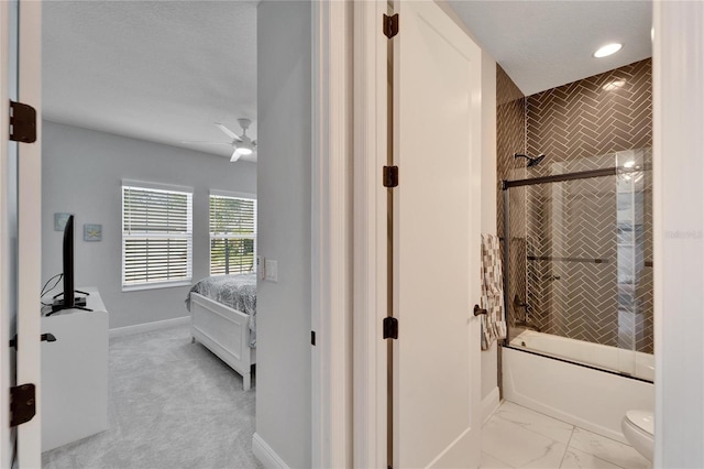 bathroom with marble finish floor, toilet, a ceiling fan, enclosed tub / shower combo, and baseboards