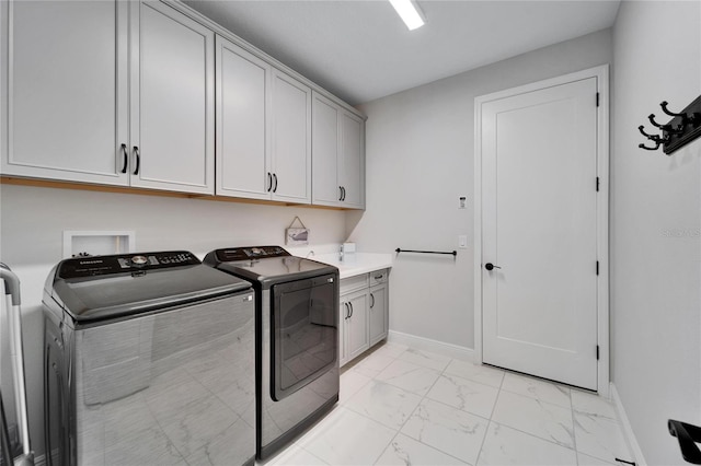 washroom with washer and dryer, marble finish floor, cabinet space, and baseboards