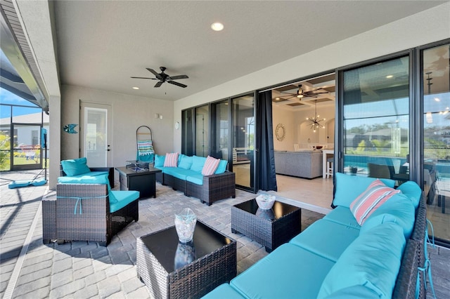 view of patio with a ceiling fan, an outdoor living space with a fire pit, and glass enclosure