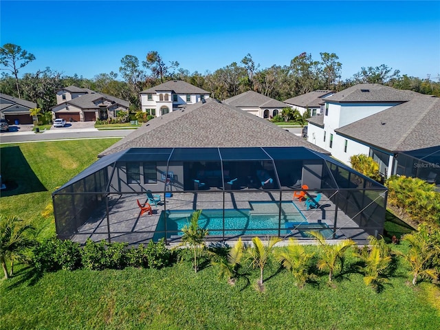 exterior space featuring a residential view, glass enclosure, a patio, and a lawn